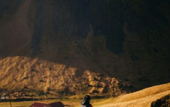 Wallpaper A Person Sitting on a Rock in the Mountains