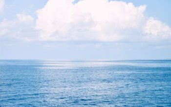 Wallpaper A Large Body of Water Under a Cloudy Blue Sky
