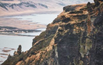 Wallpaper A Sheep Standing on a Mountaintop by a Lake