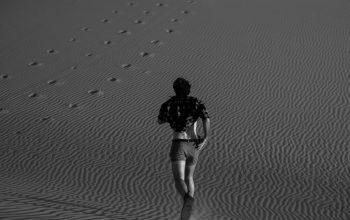 Wallpaper A Man Walking Across a Sandy Field