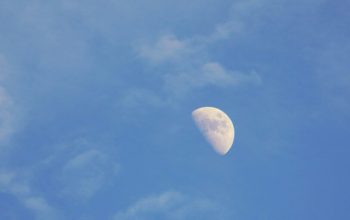 Wallpaper A Half Moon in a Blue Sky with Clouds