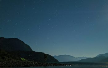 Wallpaper A Full Moon Shines Over a Mountain Lake