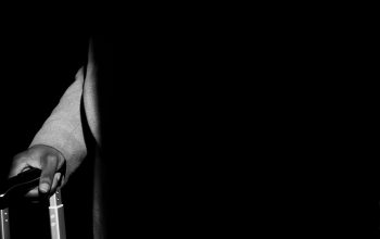Wallpaper A Black and White Photo of a Man Holding a Suitcase