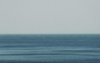 Wallpaper A Lone Boat Floating in the Middle of the Ocean