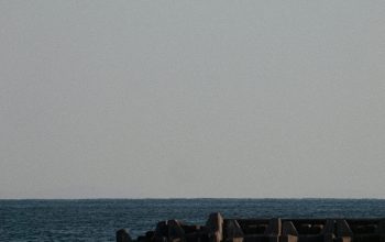Wallpaper A Large Body of Water with a Lighthouse in the Distance