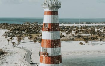Wallpaper A Red and White Lighthouse on a Sandy Beach