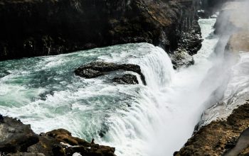 Wallpaper A Large Waterfall Over a Rocky Cliff