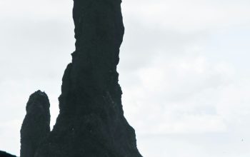 Wallpaper A Person Standing Before a Giant Rock