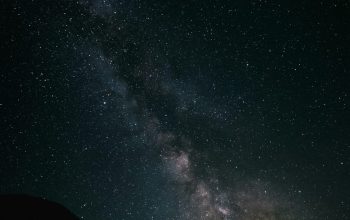 Wallpaper A Starry Night Sky with a Mountain and a Hill