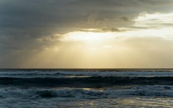 Wallpaper A Beach with Waves and a Cloudy Sky