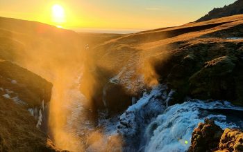 Wallpaper The Sun is Setting Over a Waterfall in the Mountains