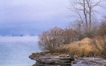 Wallpaper A Large Body of Water Next to a Rocky Shore