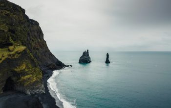 Wallpaper A Black Sand Beach with a Rock Outcropping in the Distance