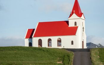 Wallpaper A Red Car Driving Past a White Church