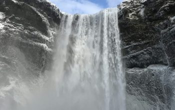 Wallpaper A Large Waterfall with Snow on the Ground