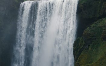 Wallpaper A Large Waterfall Cascading Down Its Sides
