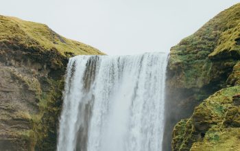 Wallpaper A Man Standing in Front of a Waterfall