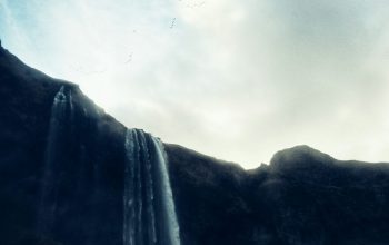 Wallpaper A Large Waterfall with Birds Flying Over It