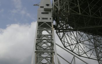 Wallpaper A Tall Metal Structure Under a Cloudy Sky