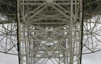 Wallpaper The Underside of a Large Metal Structure Under a Cloudy Sky