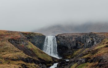 Wallpaper A Waterfall in the Middle of a Grassy Field