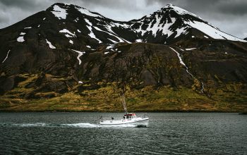 Wallpaper A Boat on Calm Waters with Majestic Mountain
