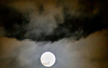 Wallpaper A Full Moon Peeking Through Clouds