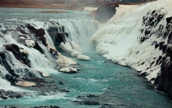 Wallpaper A River Running Through a Canyon Next to Snow-Covered Mountains