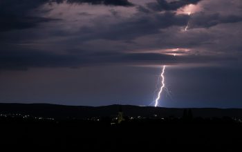 Wallpaper A Lightning Bolt Over a City at Night