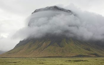 Wallpaper A Large Mountain Shrouded in Clouds