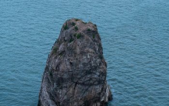 Wallpaper A Large Rock in the Middle of a Body of Water