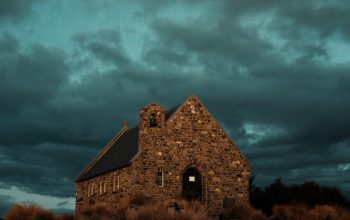 Wallpaper An Old Church on a Hill Under a Cloudy Sky