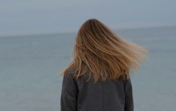 Wallpaper A Woman Standing on a Beach Looking at the Ocean