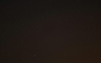 Wallpaper The Night Sky is Filled with Stars Above a Hill