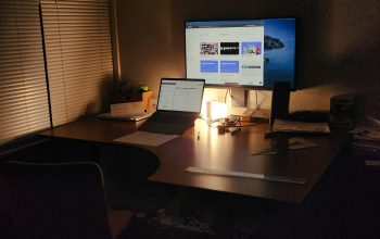 Wallpaper A Dimly Lit Desk with Laptop and Monitor