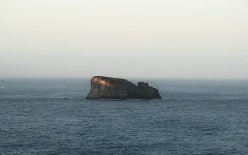 Wallpaper A Solitary Rock Formation Rises from the Sea