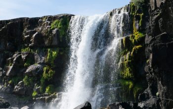 Wallpaper A Beautiful Waterfall Cascades Over Rocky Terrain